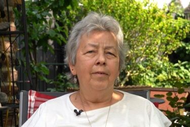 DMÖ-Patientin H. Eichhorn sitzt im Garten und lächelt
