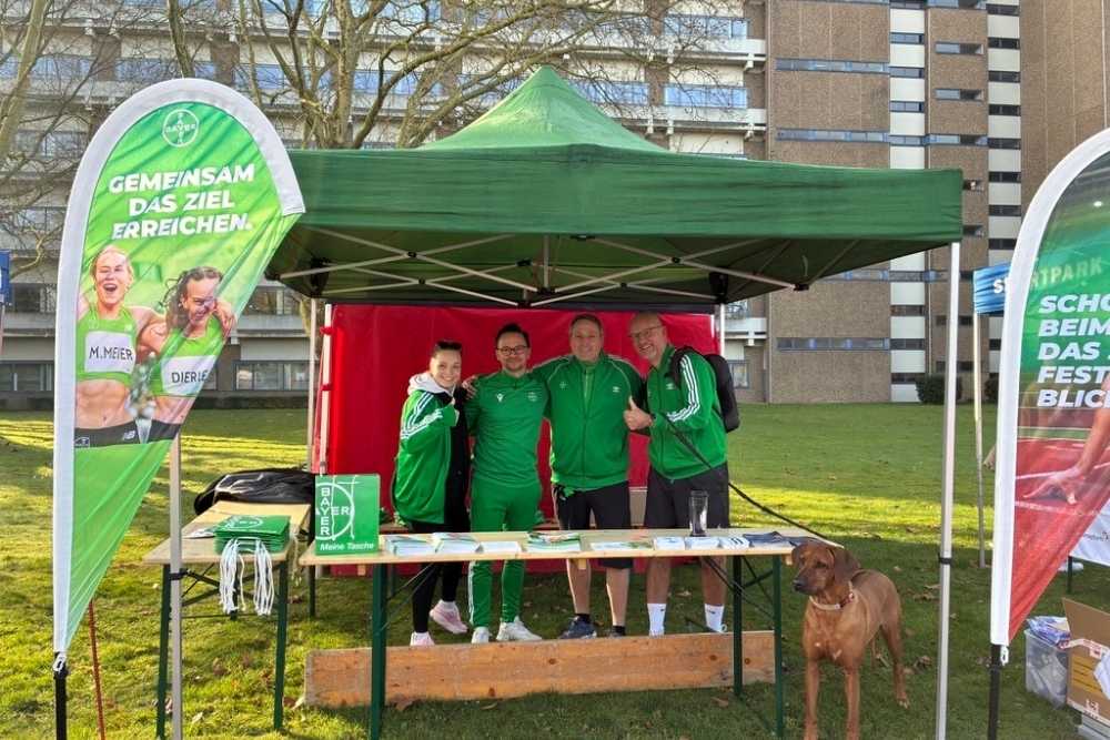 Rund um das Bayer-Kreuz 2026: Vier Läufer:innen posieren in einem Zelt